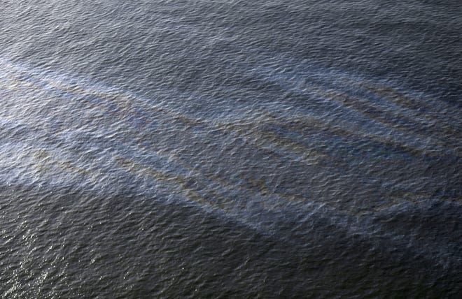 An oil sheen drifts from the site of the former Taylor Energy oil rig in the Gulf of Mexico, off the coast of Louisiana, March 31, 2015. A federal lawsuit that Taylor Energy Co. filed Thursday, Dec. 20, 2018, in New Orleans asks the court to throw out Coast Guard Capt. Kristi Luttrell's Oct. 23 administrative order. The suit claims the Coast Guard's actions ignored "well-verified scientific conclusions" and were taken in response to "adverse publicity." [AP Photo/Gerald Herbert, File]