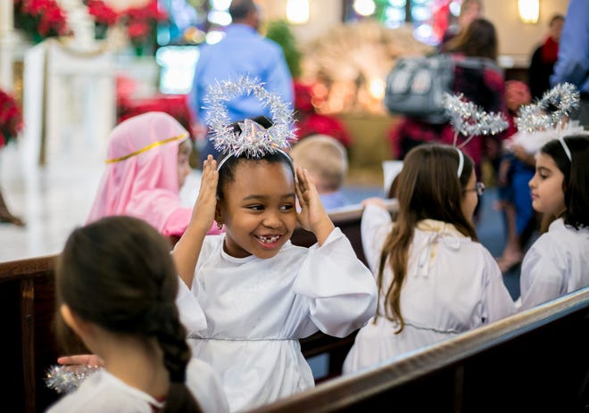 St. Ann Catholic School first grader April DuJour adjusts her costume with her nativity pageant classmates during the nativity mass in downtown West Palm Beach Monday.  [RICHARD GRAULICH/palmbeachpost.com]