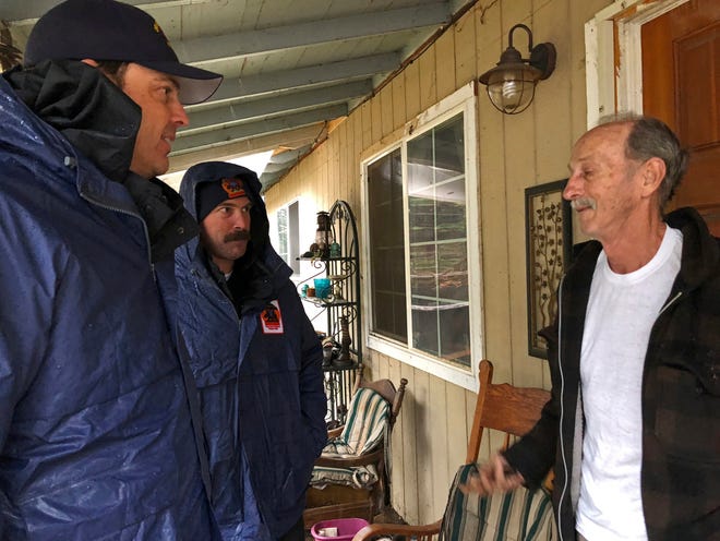 FILE - In this Nov. 23, 2018, file photo, Craig Covey, task force leader for the Orange County search team, left, and David Harper talk to resident Stewart Nugent outside his Paradise, Calif., home. Covey and several team members took two giant brown bags full of lunch to Nugent, who stayed in his home and fought off flames. (AP Photo/Kathleen Ronayne, File)