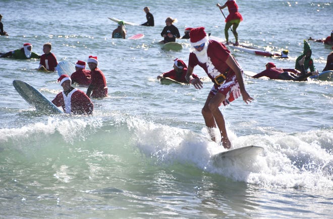 Thousands showed up in downtown Cocoa Beach for the annual Christmas Eve Surfing Santas event with hundreds of surfing Santas taking to the waves. The event now raises money for the Florida Surf Museum and Grind for Life. [Malcolm Denemark/Florida Today via AP]