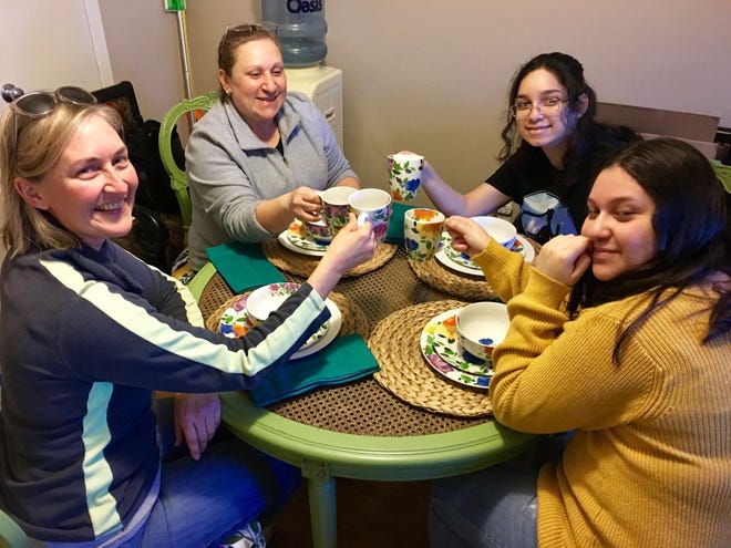 Wendy Conklin, left, donated a new table and chairs from her line, Chair Whimsy, to the Lugo family. Conklin, Mirtha Lugo, 53, and Lugo's daughters Andrea Arias Zarate, 15, and Giselle Arias Zarate, 14, toast on Sunday, when Conklin came to deliver the table. [Sierra Randall/Foundation Communities]