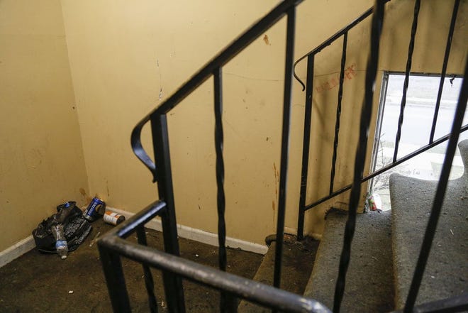 Empty alcohol containers and other trash litter a stairway in a North Side apartment building during an inspection by Columbus city code enforcement officers last year. [Joshua A. Bickel/Dispatch file photo]