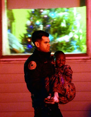 A police officer carries an injured boy near the scene of the fatal house fire in Avon.  [Marc Vasconcellos/The Enterprise via AP]