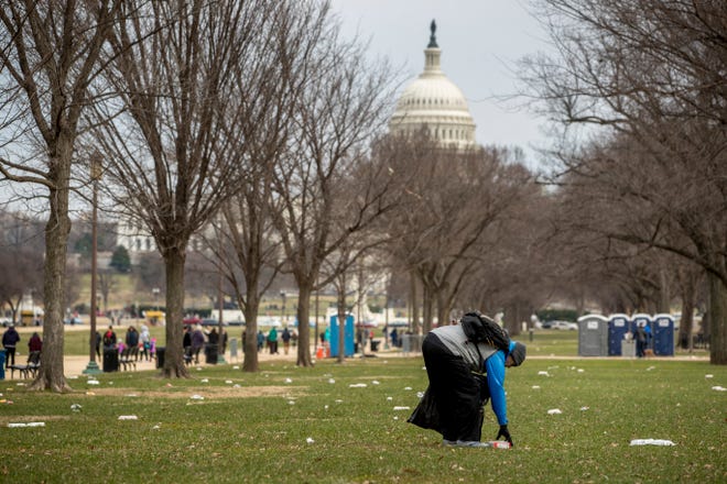 The Capitol building is visible as a man who declined to give his name picks up garbage during a partial government shutdown on the National Mall in Washington, Tuesday, Dec. 25, 2018. (AP Photo/Andrew Harnik)