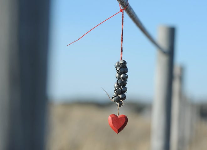 A string of bells and a heart hang on the fencing along West Dennis Beach.