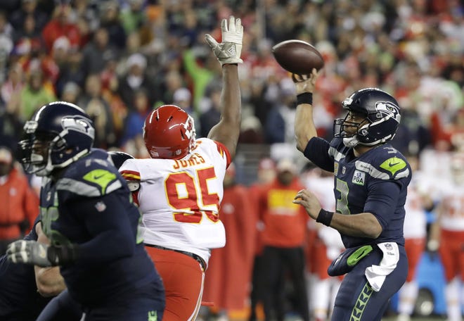 Seattle Seahawks quarterback Russell Wilson, right, passes under pressure by Kansas City Chiefs defensive end Chris Jones (95) during the second half of an NFL football game Sunday in Seattle. [Elaine Thompson/The Associated Press]
