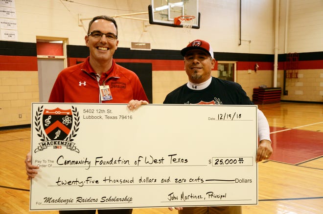 Coronado Principal Jerry Adams, left, and Mackenzie Principal John Martinez pose with a giant check made out for the Mark and Becky Lanier Raider/Mustang Scholarship. The check presentation was made during halftime of a teachers vs. students basketball game that helped to raise money for the scholarship. [Provided by Lubbock ISD]