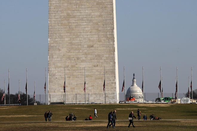 People walk near the Washington Monument, with the U.S. Capitol in the background, Wednesday, Dec. 26, 2018, as the partial government shutdown continues in Washington. A shutdown affecting parts of the federal government appeared no closer to resolution Wednesday, with President Donald Trump and congressional Democrats locked in a hardening standoff over border wall funding that threatens to carry over into January. [ JACQUELYN MARTIN / AP ]