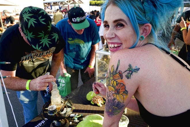 In this Oct. 20 photo, bud tender Kansas, right, offers up a puff of cannabis concentrates at the Turtle Puddles' booth at the cannabis-themed Kushstock Festival at Adelanto, Calif.  [AP File Photo]