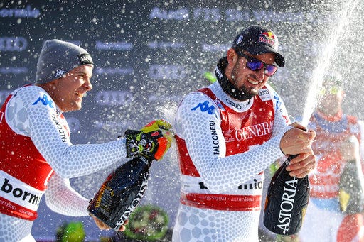 Second placed Italy's Christof Innerhofer, left, and first placed Italy's Dominik Paris celebrate with sparkling wine on the podium at the end of a ski World Cup Men's Downhill in Bormio, Italy, Friday, Dec. 28, 2018. (AP Photo/Marco Trovati)