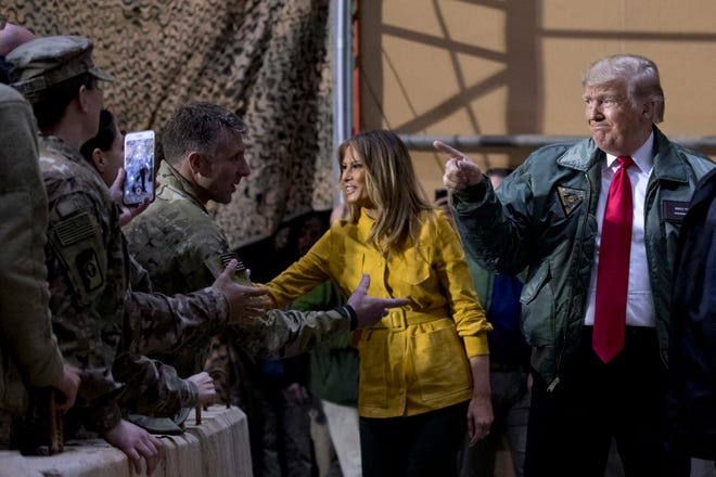 President Donald Trump and first lady Melania Trump greet members of the military as they arrive for a hanger rally at Al Asad Air Base, Iraq, on Wednesday. In a surprise trip to Iraq, President Donald Trump on Wednesday defended his decision to withdraw U.S. forces from Syria where they have been helping battle Islamic State militants. [Andrew Harnik/The Associated Press]