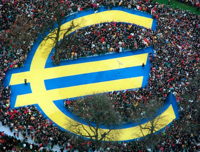 Thousands of people stand around a huge euro symbol displayed in a park in Frankfurt's banking district on Jan. 1, 1999, the day the euro currency was launched.  [AP ARCHIVE]