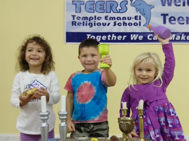 Temple Emanu-El Tot Shabbat preschoolers Ziva Sheslow, Abner Beck, and Josie Beck got into the Shabbat spirit with a pretend challah, ritual kiddush cup and grape juice at Temple Emanu-El's recent Shabbat celebration for young Jewish and interfaith families. [PROVIDED PHOTO]