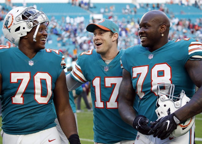 Miami Dolphins quarterback Ryan Tannehill celebrates with offensive tackles Ja'Wuan James and Laremy Tunsil earlier this season [JOEL AUERBACH/AP]