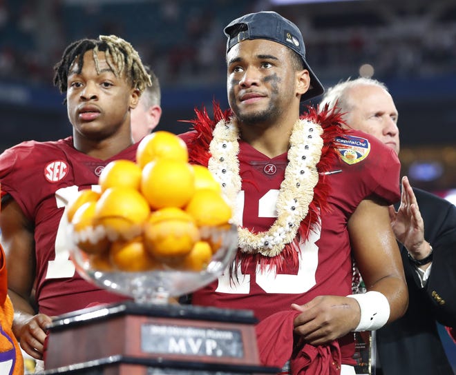 Alabama quarterback Tua Tagovailoa (13) stands next to the MVP trophy for the offensive player of the game at the end of the Orange Bowl against Oklahoma. [Wilfredo Lee/Associated Press]