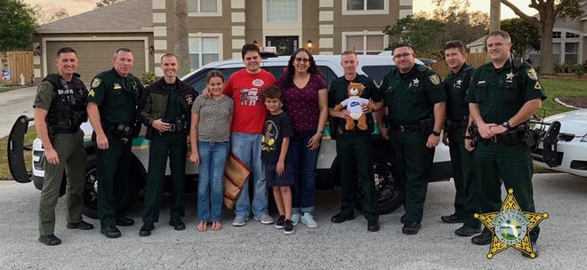 Members of the Lake County Sheriff's Office pose with Isabella Miller and her family, and her new Charmin Teddy bear. {FACEBOOK]