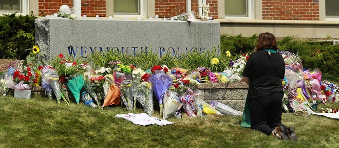 A woman takes a moment to remember slain police Michael Chesna in front of Weymouth Police headquarters, Winter Street on Monday, July 16, 2018. Greg Derr/ The Patriot Ledger