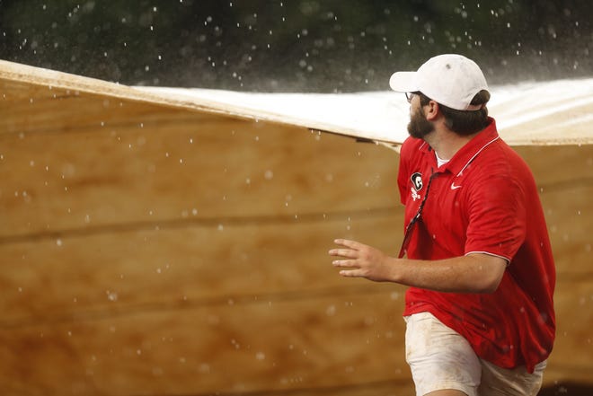 A member of the game crew rushes to cover the field as rain hit during an NCAA softball Super Regional game between Georgia and Tennessee in Athens, Ga., Friday, May 25, 2018. [Joshua L. Jones/Athens Banner-Herald]