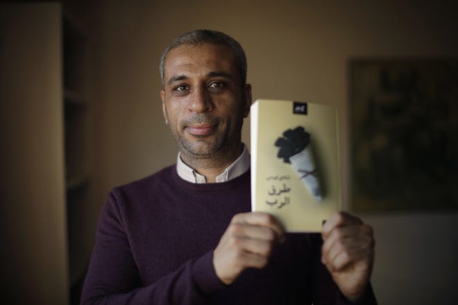 In this Tuesday, Dec. 4, 2018 photo, journalist and author Shady Lewis Botros poses with a copy of his book, "Ways of the Lord," in London. The new Arabic-language novel, the authorþÄôs first, explores the lives of Egyptian Christians, dealing with discrimination but also a Church aligned with a state seeking to control them. (AP Photo/Matt Dunham)