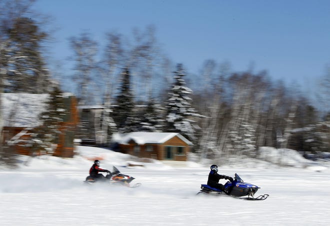 Riders cross Rangeley Lake on snowmobiles in Rangeley, Maine. An annual weekend for snowmobilers registered in Maine, New Hampshire and Vermont to legally ride in any of the three states has come to an end in January 2019 due to a change in laws. (AP photo/Robert F. Bukaty, file)