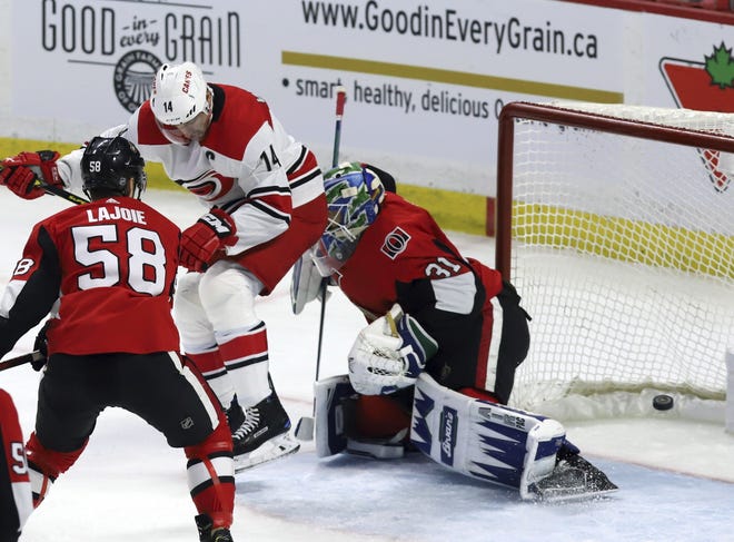 Carolina's Justin Williams (14) screens and deflects the puck past Ottawa goaltender Anders Nilsson in the third period for the game-winning score Sunday. [Fred Chartrand/The Canadian Press via AP]