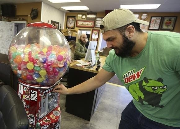At Underground Tattoo Station, Trey Crumrine puts a quarter in a gumball machine to receive a random design. Two containers accidentally were delivered, so Crumine chose one without knowing what he'd get. (GateHouse Media Ohio / Jonathan Quilter, The Columbus Dispatch)