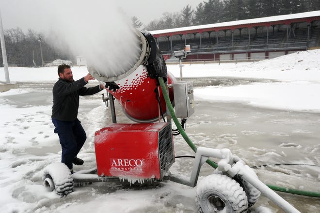 Josh Little from East Coast Snocross aims a snow gun at the Rochester Fairgrounds to make snow for this weekend's event. [John Huff/Fosters.com]