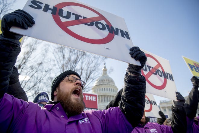 The Capitol Dome is visible behind Grant Mulkey, with the National Air Traffic Controllers Association, and others who hold signs and shout in unison to open the government "NOW!" on Capitol Hill in Washington on Thursday. [Andrew Harnik/AP Photo]
