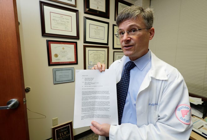 In this Dec. 20, 2018, photo, Dr. Jeffrey Clemons, a pelvic reconstructive surgeon, poses for a photo in Tacoma, Wash., with a letter to state Attorney General Bob Ferguson that he helped draft and was signed by more than 60 Washington state surgeons. The letter argues that Ferguson's consumer-protection lawsuit against Johnson & Johnson and its Ethicon Inc. subsidiary over products used to treat pelvic floor disorders and incontinence in women might scare patients away from the best treatment options. (AP Photo/Ted S. Warren)