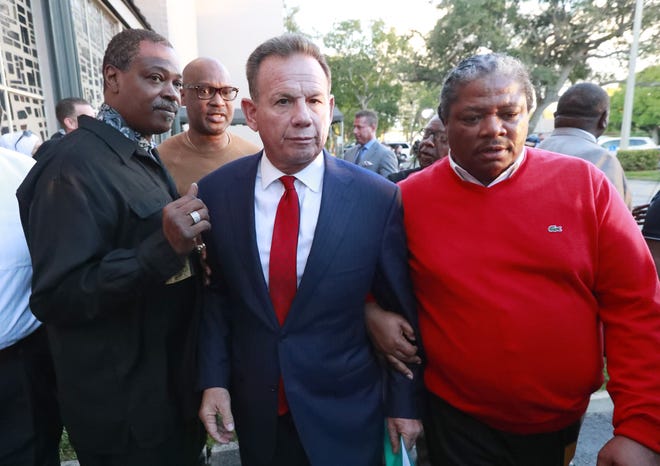 Suspended Broward County Sheriff Scott Israel, center, leaves a news conference surrounded by supporters Friday in Fort Lauderdale. [AP Photo/Wilfredo Lee]