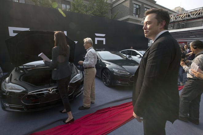 Tesla Motors CEO Elon Musk, right, looks on as a set of Tesla Model S sedans are delivered to its first customers in China at an event in Beijing in April of 2014. [AP / Ng Han Guan]