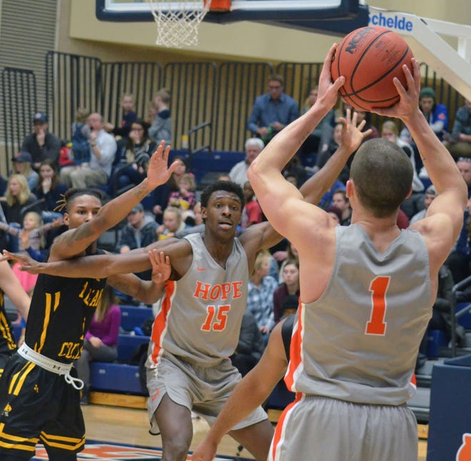 Hope's Jason Beckman (right) looks to pass the ball to Dennis Towns on Saturday against Adrian at DeVos Fieldhouse. [Dan D'Addona/Sentinel staff]