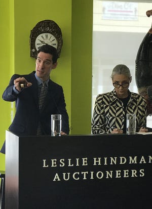 Auctioneer Corbin Horn, left, assisted by Donna Tribby, holds a gavel as he gestures to a bidder at a 2018 auction at the West Palm Beach showroom of Leslie Hindman Auctioneers. Hindman LLC has acquired Leslie Hindman Auctioneers and Cowan's Auctions. [Darrell Hofheinz / Daily News file photo]