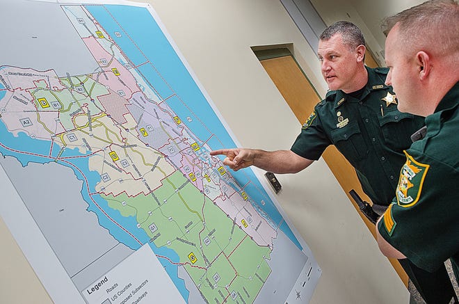 St. Johns County Sheriff's Office Cmdr. Bill Werle and Sgt. West Kennedy look at a map showing new deputy patrol areas at their headquarters in St. Augustine on Monday. [PETER WILLOTT/THE RECORD]