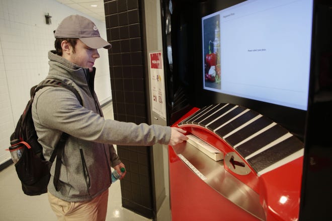 Zach Pryfogle, 19, an Ohio State freshman from Westerville, pulls his freshly-baked pepperoni pizza from the new Pizza ATM on Tuesday, Jan. 15, at Ohio State University's Morrill Tower in Columbus. Students can currently choose from pepperoni and cheese pizza. (Joshua A. Bickel/Dispatch)