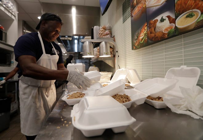 Tony Mertin packages hot meals at the Chef Creole restaurant at Miami International Airport, Tuesday, Jan. 15, 2019, in Miami. The restaurant is offering free lunch and dinner to federal airport employees affected by the government shutdown. (AP Photo/Lynne Sladky)