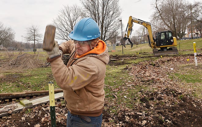 Angel Huanga with Mizu Contracting, puts stakes in the ground for a fence, during the beginning stages of replacing Imagination Island Park in Williamson Park with a new tot lot on Wednesday, in Morrisville. The tot lot is due to open to the public by Mid-April with a playground for older children to follow. [KIM WEIMER / STAFF PHOTOJOURNALIST]