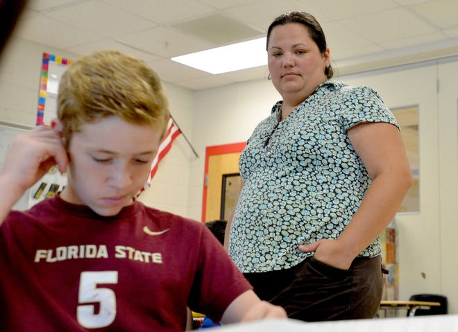 Teacher Shaunna Farley looks over Micheal Woodley's work in a seventh-grade personalized learning class at Carver Heights Middle School on Wednesday, Aug. 17, 2016 in Leesburg, Fla. School district officials say personalized learning is an effective tool in helping students, but at the same time they say not enough study has been done on personalized learning. (Amber Riccinto/ Daily Commercial)