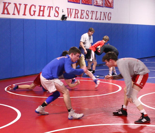 Tyler Masters (front left) spars with teammate Cael Woods during practice in the West Holmes wrestling room as assistant coach Greg Woods works with other Knights in the background. Masters is currently 17-2 wrestling at 120, while Woods is 21-0 with 17 pins at 113.