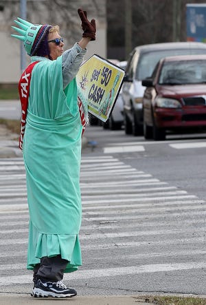 Teresa Jenkins dressed as "Miss Liberty", waves to motorists on Franklin Boulevard Thursday morning near the Liberty Tax Service location at 117 N. Myrtle School Road in Gastonia. [JOHN CLARK/THE GASTON GAZETTE]