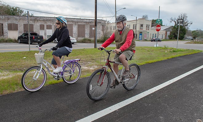Sally and Rick Willman, who are visiting the area from Indiana, ride their bikes on Wednesday through Hastings on a recently complete section of a bike trail that now links Palatka to Vermont Heights on State Route 207. [PETER WILLOTT/THE RECORD]