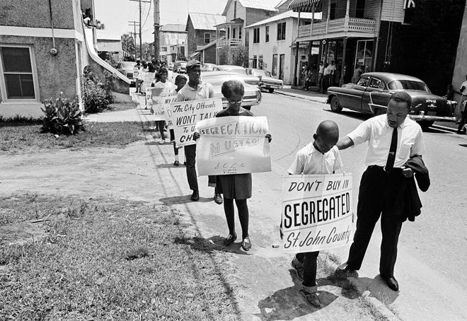 Dr. Martin Luther King, Jr. gives a young boy a pat on the back as a group of mostly children started to picket on Washington Street in St. Augustine on June 10, 1964. King stayed in St. Augustine several times during his fight for civil rights, and he was even arrested here. [THE ASSOCIATED PRESS/FILE]