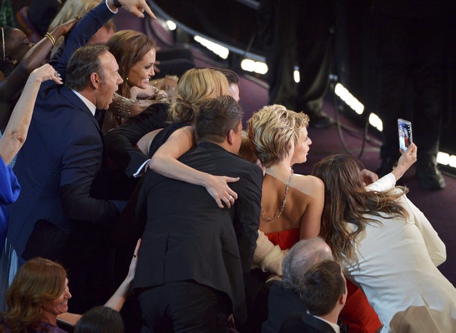 During the 2014 Academy Awards, host Ellen DeGeneres (holding phone) introduced a memorable moment into the ceremony when she took a selfie with celebrities in the front row [AP FILE PHOTO]