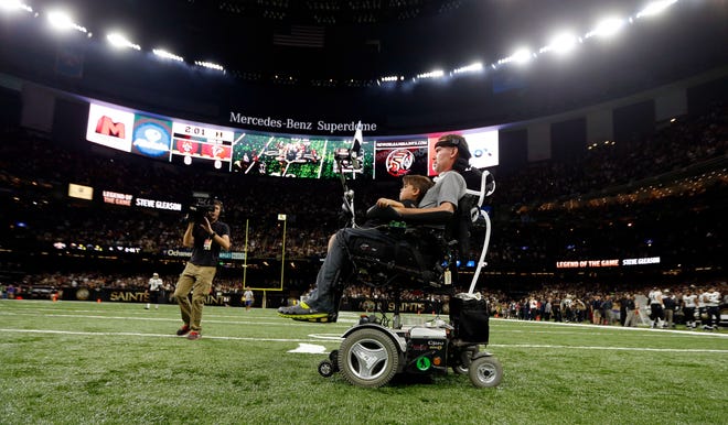 FILE - In this Sept. 26, 2016, file photo, former New Orleans Saints player Steve Gleason rides onto the field with with his son Rivers before an NFL football game against the Atlanta Falcons in New Orleans. He's the Saints' biggest fan and the perfect symbol of a city that knows a thing or two about overcoming hardship. As the Big Easy goes for another championship, Gleason is along for the ride. Even though his body failed him, perhaps because of the game he loved so much, he never lost the will to live and love and make a difference. (AP Photo/Gerald Herbert, File)