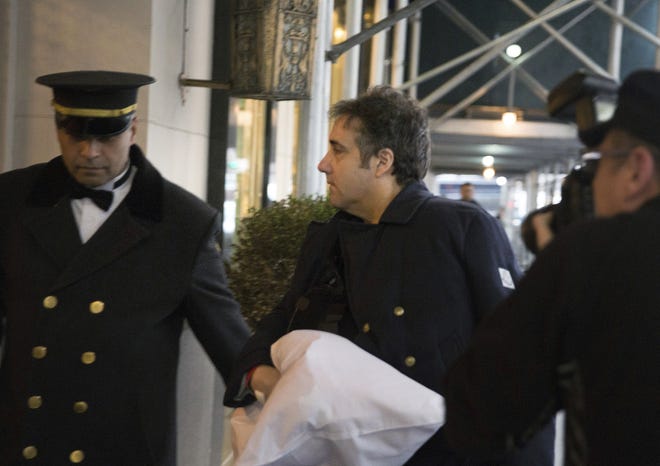Michael Cohen arrives at his home in New York with his left arm in a sling supported by a pillow Friday. [AP Photo/Kevin Hagen]