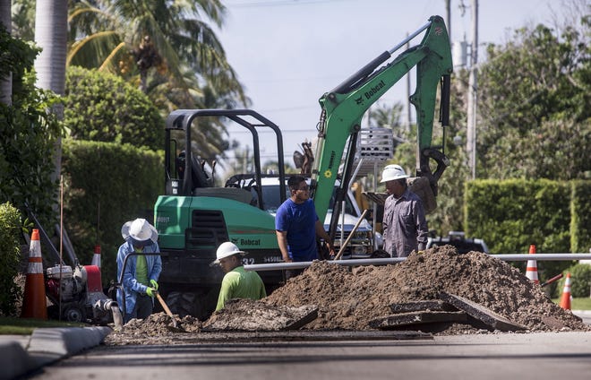 Workers use a backhoe to open up the road along North Ocean Boulevard just south of Indian Road in June to install cable lines for AT&T. The current estimate is that construction will total $103 million. 

 [Damon Higgins / Daily News file photo]