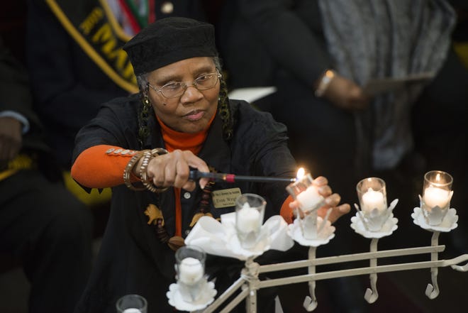 MLK Day Observance Association Board Member Gena Wright lights candles in memory of those lost in 2018 at the Citywide Martin Luther King Jr. Memorial Worship Service on Sunday. [Will Peebles/Savannahnow.com]