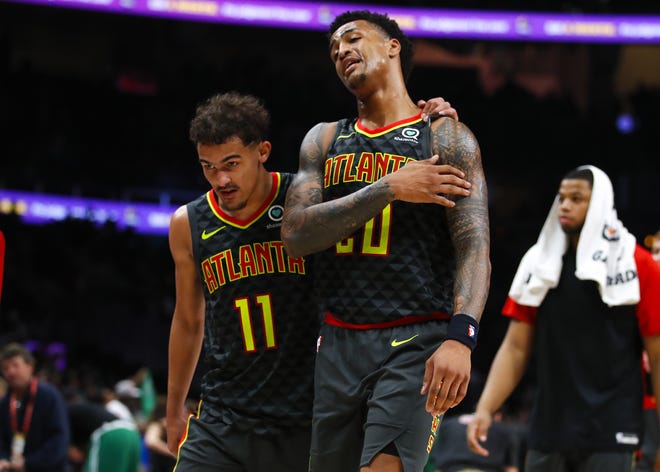 Hawks guard Trae Young (11) and forward John Collins (20) leave the court after the team's loss against the Celtics on Saturday in Atlanta. [TODD KIRKLAND/THE ASSOCIATED PRESS]