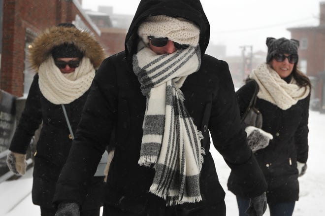 Julia Beebe, center, Shannon Amore, left, and Jessica Lynch brave a winter storm to keep a lunch date, Sunday in Portland, Maine. Scarves, hoods and gloves were necessary for New England residents venturing outdoors as the region endures a storm that can dump up to 18 inches of snow. [Robert F. Bukaty/Associated Press]