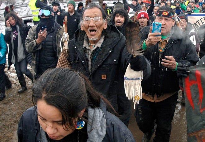 FILE - In this Feb. 22, 2017, file photo, a large crowd representing a majority of the remaining Dakota Access Pipeline protesters, including Nathan Phillips, center with glasses, march out of the Oceti Sakowin camp before the deadline set for evacuation of the camp near Cannon Ball, N.D. Phillips says he felt compelled to get between a group of black religious activists and largely white students with his ceremonial drum to defuse a potentially dangerous situation at a rally in Washington. (Mike McCleary/The Bismarck Tribune via AP, File)